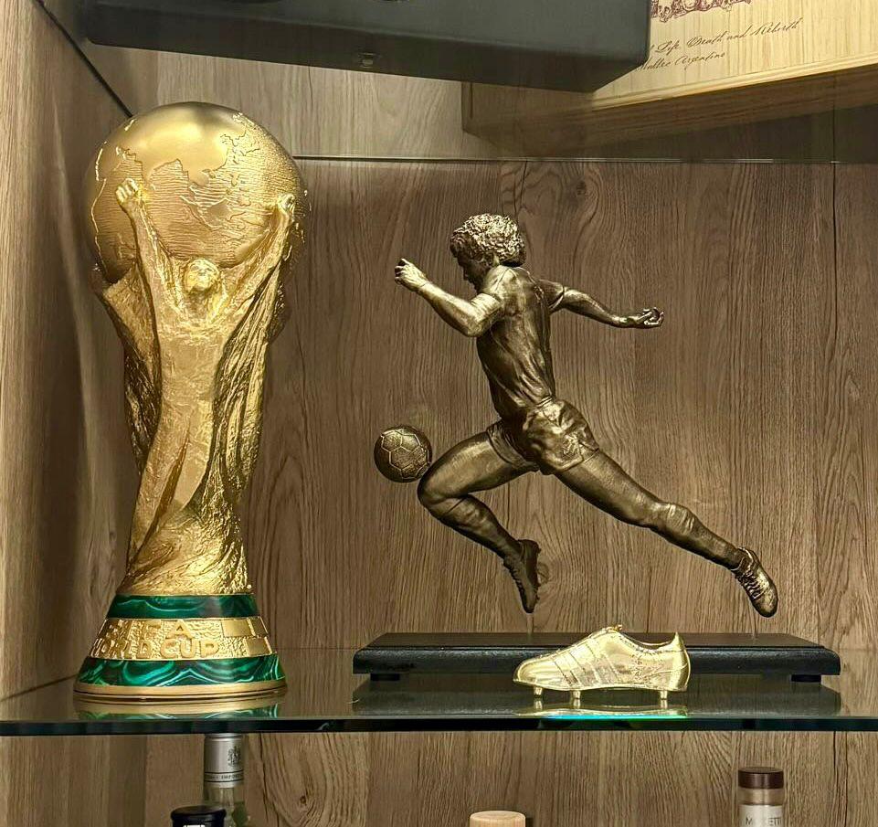 Copa del Mundo exhibida junto a figura de jugador